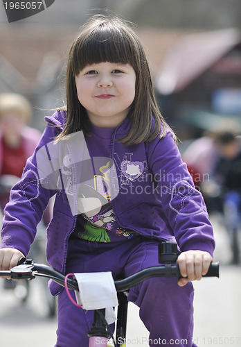 Image of cute little girl driving bicyle at sunny day