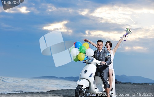 Image of just married couple on the beach ride white scooter