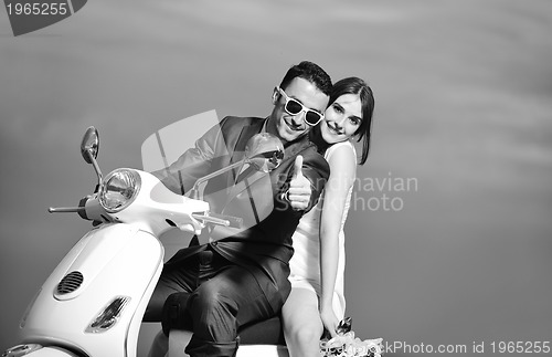 Image of just married couple on the beach ride white scooter