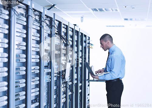 Image of businessman with laptop in network server room