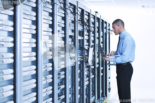 Image of businessman with laptop in network server room