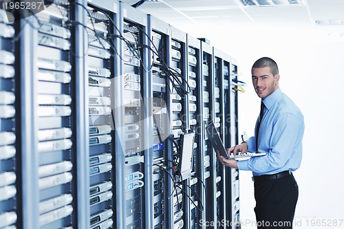 Image of businessman with laptop in network server room