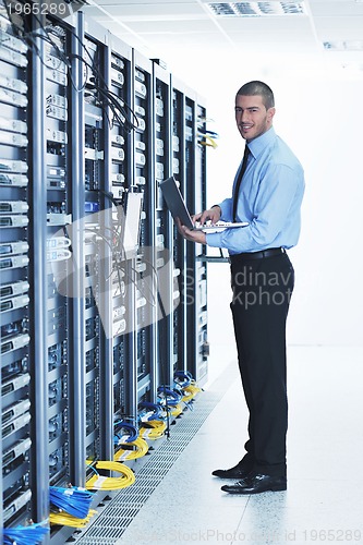 Image of businessman with laptop in network server room