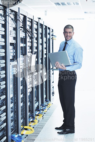 Image of businessman with laptop in network server room