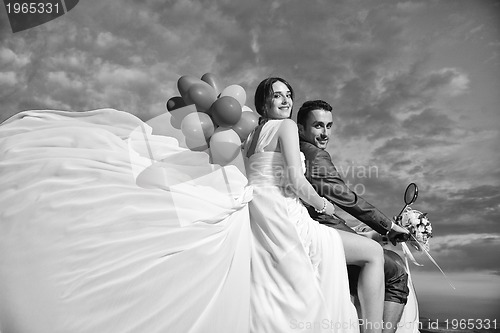 Image of just married couple on the beach ride white scooter