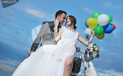 Image of just married couple on the beach ride white scooter