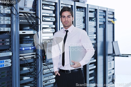 Image of businessman with laptop in network server room