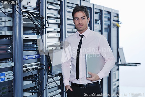 Image of businessman with laptop in network server room