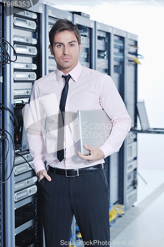 Image of businessman with laptop in network server room