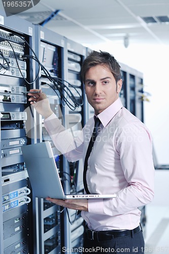 Image of businessman with laptop in network server room