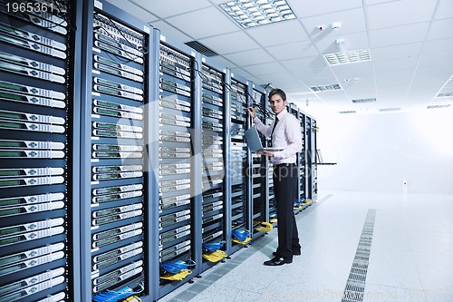 Image of businessman with laptop in network server room