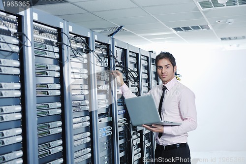 Image of businessman with laptop in network server room