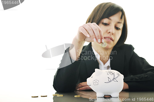 Image of business woman putting coins money in piggy bank