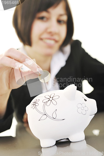 Image of business woman putting coins money in piggy bank