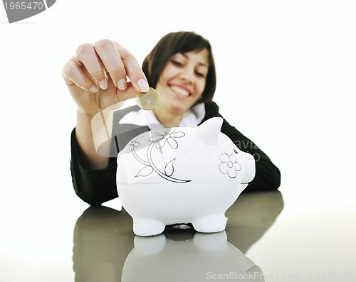 Image of business woman putting coins money in piggy bank