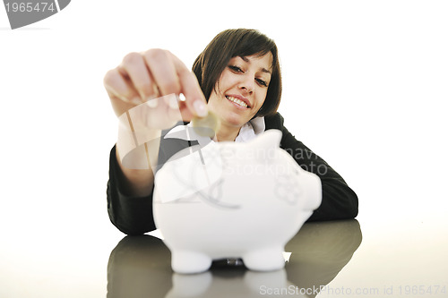 Image of business woman putting coins money in piggy bank