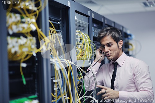 Image of it engeneer talking by phone at network room