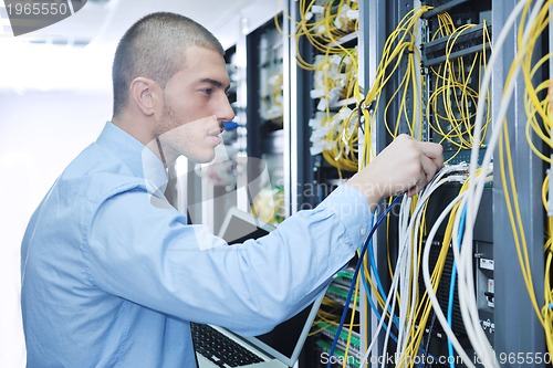 Image of businessman with laptop in network server room