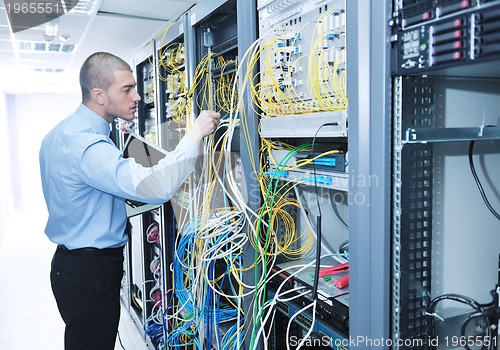 Image of businessman with laptop in network server room