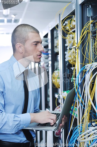 Image of businessman with laptop in network server room