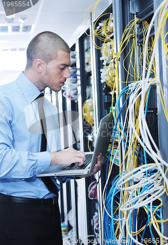 Image of businessman with laptop in network server room