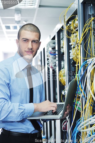 Image of businessman with laptop in network server room