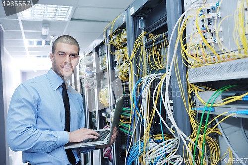 Image of businessman with laptop in network server room