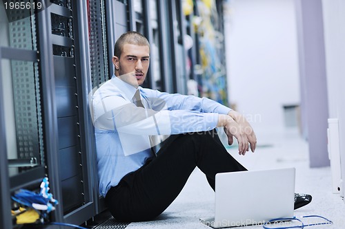 Image of businessman with laptop in network server room