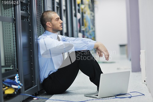Image of businessman with laptop in network server room