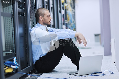 Image of businessman with laptop in network server room