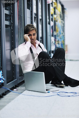 Image of businessman with laptop in network server room