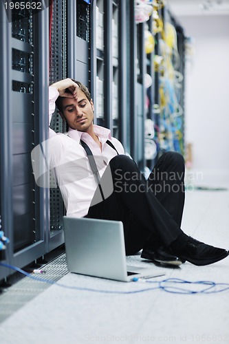 Image of businessman with laptop in network server room