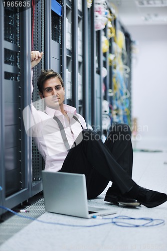 Image of businessman with laptop in network server room