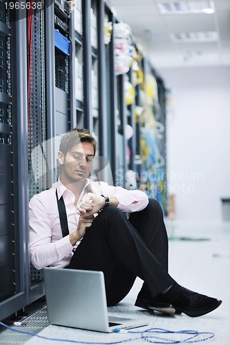 Image of businessman with laptop in network server room