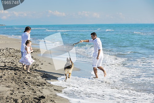 Image of happy family playing with dog on beach