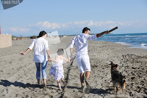 Image of happy family playing with dog on beach