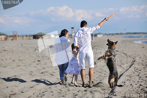 Image of happy family playing with dog on beach