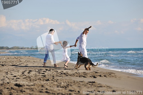 Image of happy family playing with dog on beach