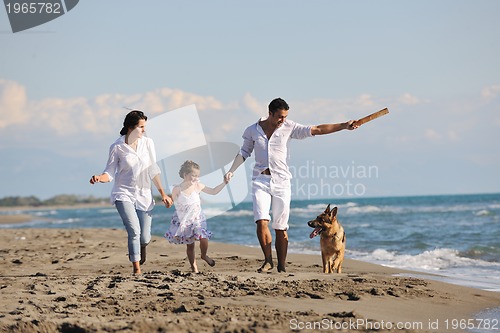 Image of happy family playing with dog on beach