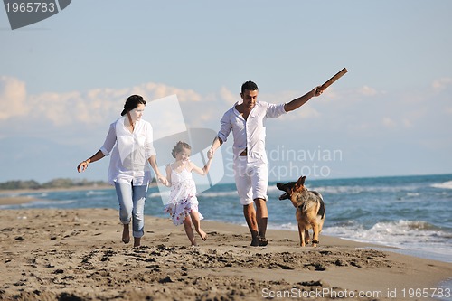 Image of happy family playing with dog on beach