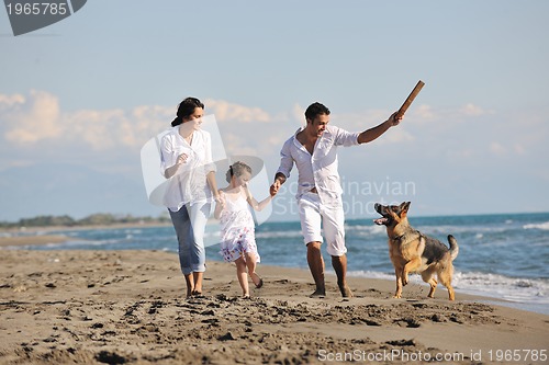 Image of happy family playing with dog on beach