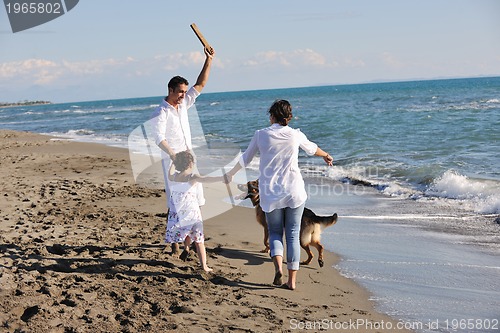 Image of happy family playing with dog on beach