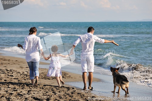 Image of happy family playing with dog on beach