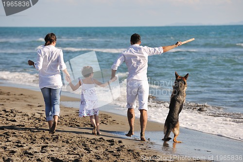 Image of happy family playing with dog on beach