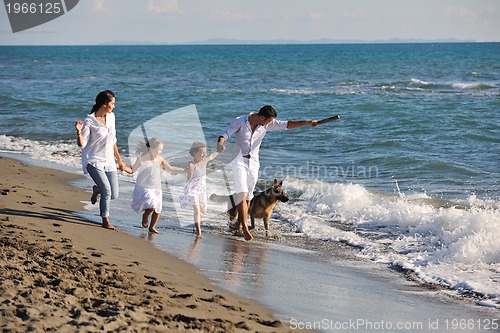 Image of happy family playing with dog on beach