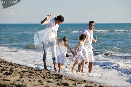 Image of happy family playing with dog on beach