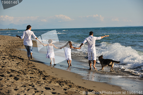Image of happy family playing with dog on beach