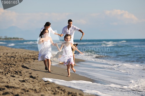 Image of happy family playing with dog on beach