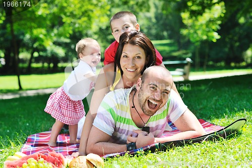 Image of happy young couple with their children have fun at park
