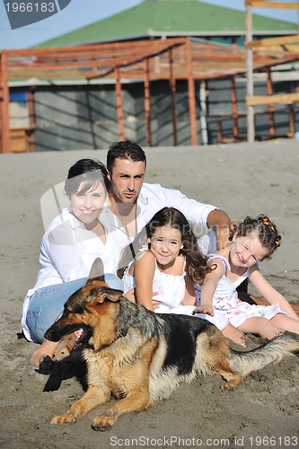 Image of happy family playing with dog on beach